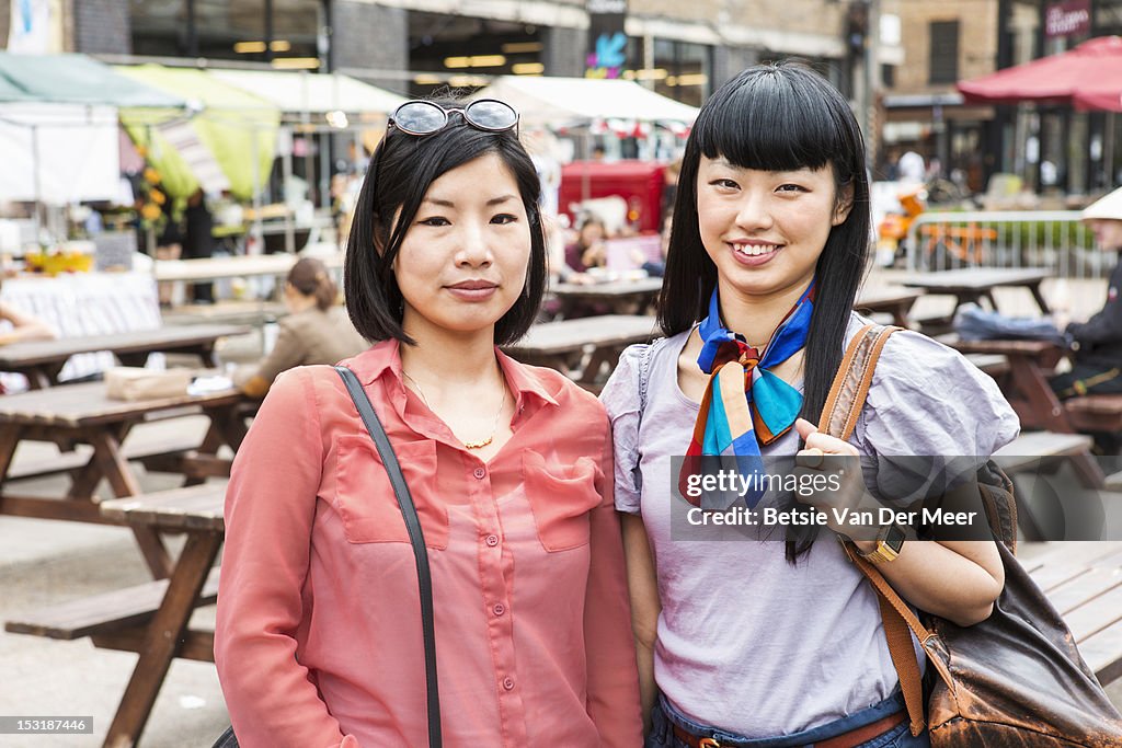 Portrait of two asian women at urban market.