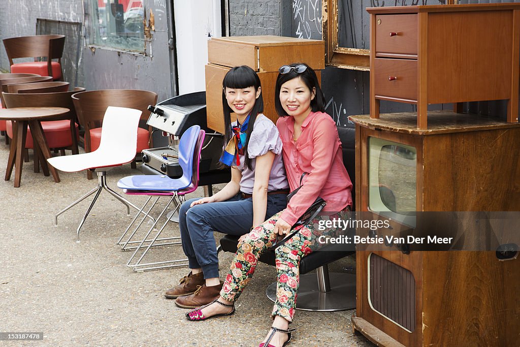 2 asian women sitting on chair at market shop.