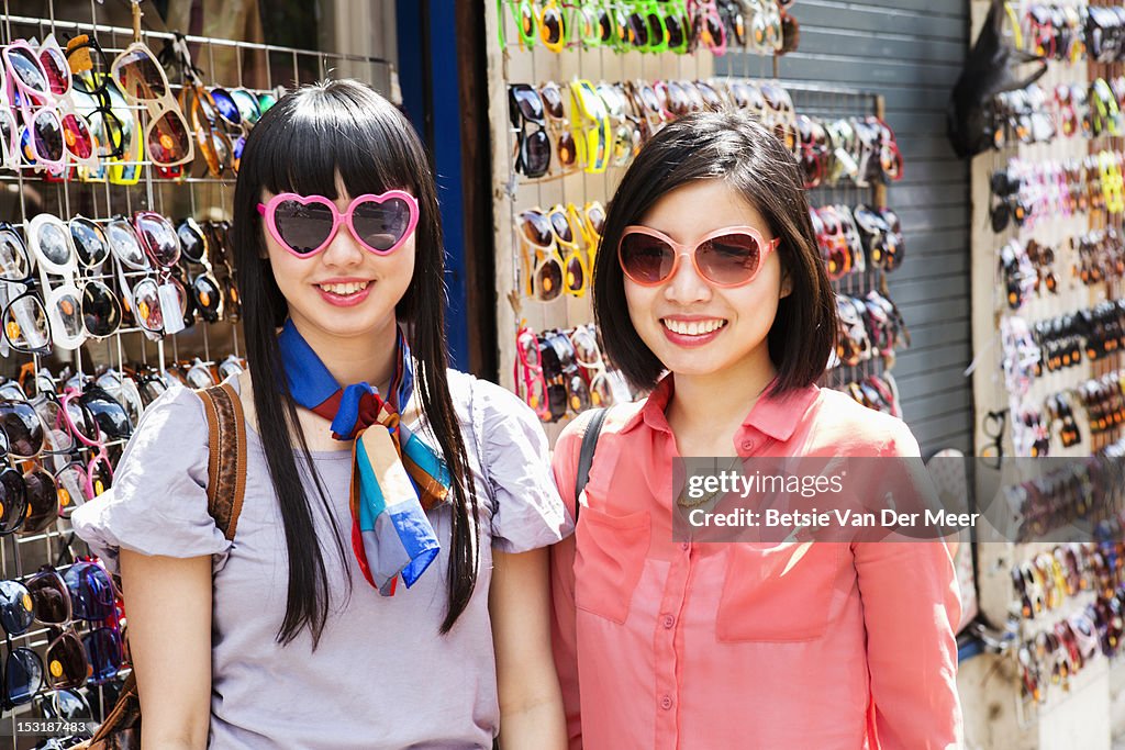 Asian women with chosen sunglasses at market stall