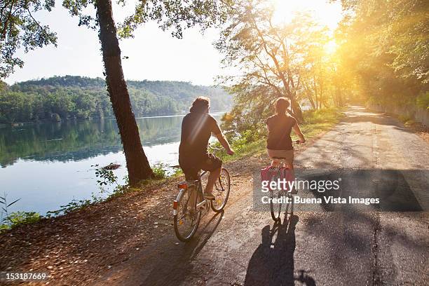 couple on bicycle along a river - pavia italy stock pictures, royalty-free photos & images