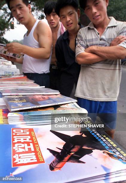 Several men stand around a street-side news stand featuring a magazine with a surface to air missile launcher on its cover 21 July 1999 in downtown...