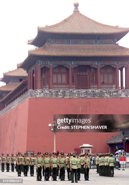 Dwarfed by part of the ancient Forbidden City's gate, Chinese soldiers practice marching with their bayonettes 04 June 1999 at their barracks next to...