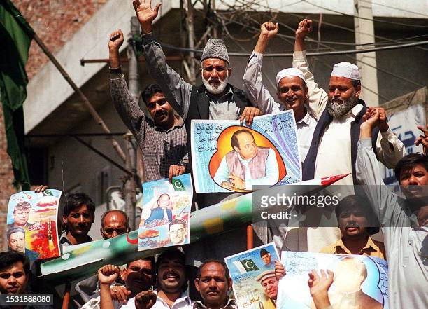 Supporters of the ruling Pakistan Muslim League celebrate with a mock Shaheen missile and portraits of premier Nawaz Sharif and prominent scientist...