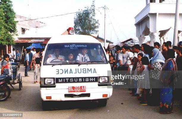 Residents of Lhokseumawe look on as an ambulance carries the bodies 10 January of four victims tortured to death in military custody. The four killed...