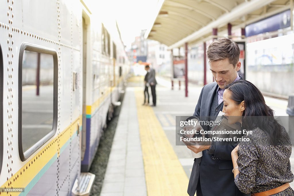 Business people using cell phone at train station