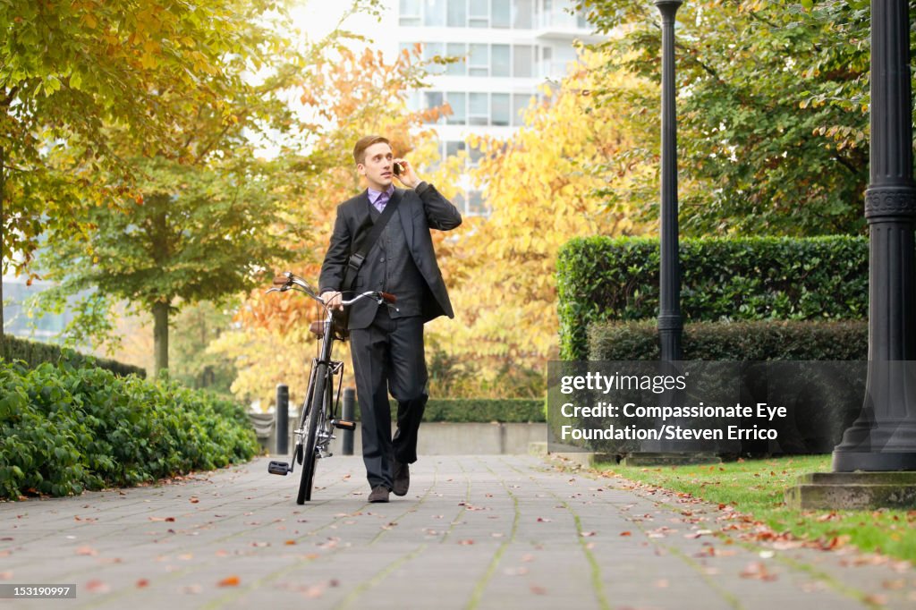 Businessman with bicycle using mobile phone