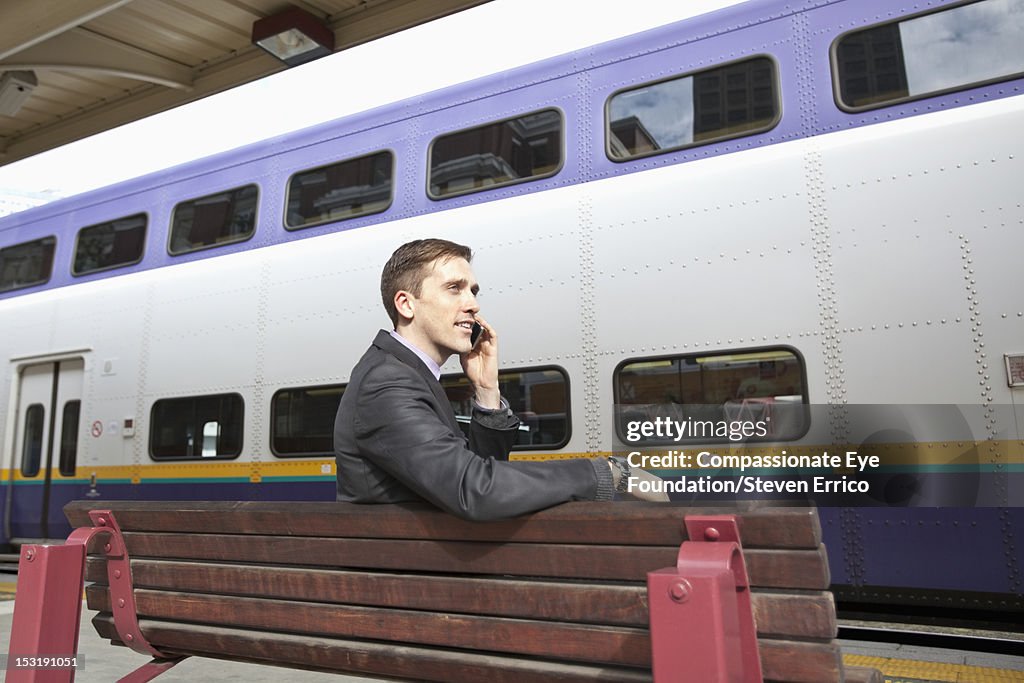 Businessman at train station using mobile phone