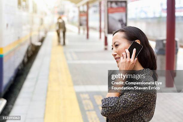 Businesswoman At Train Station Using Mobile Phone, Foto de stock