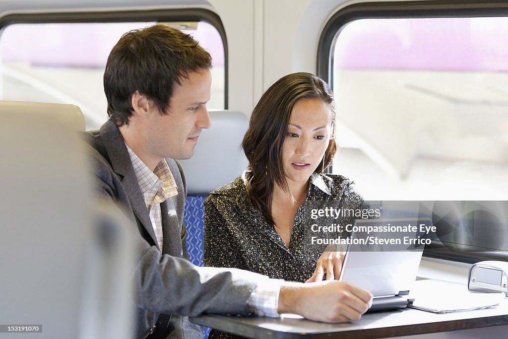 Business people working on train with laptop