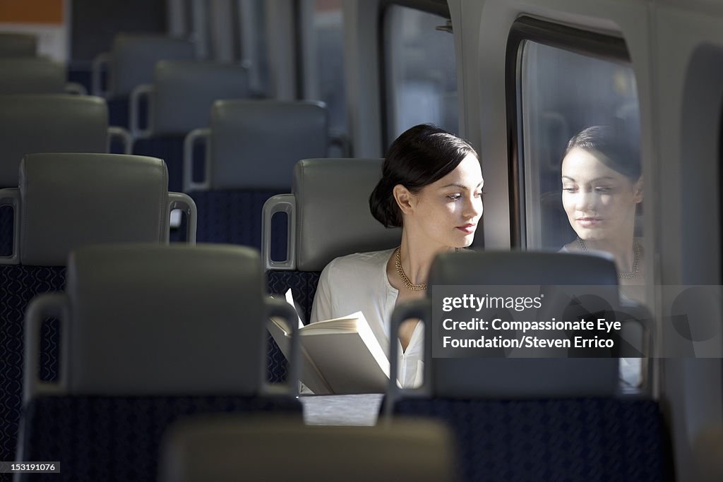 Young woman on train reading a book