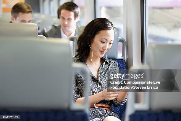 young woman on train using mobile phone - compassionate eye foundation stock-fotos und bilder