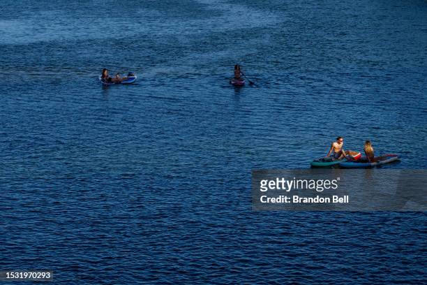 People sit on river boards in the Colorado River on July 10, 2023 in Austin, Texas. Record-breaking temperatures continue soaring as prolonged...