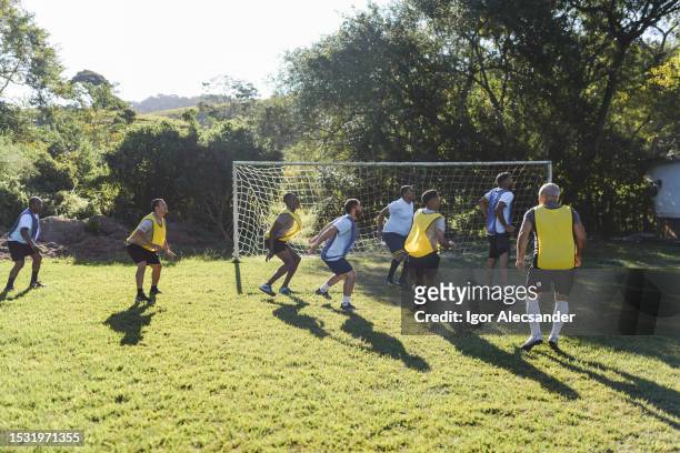 co-workers playing a casual soccer match on sunday - friendly match stockfoto's en -beelden