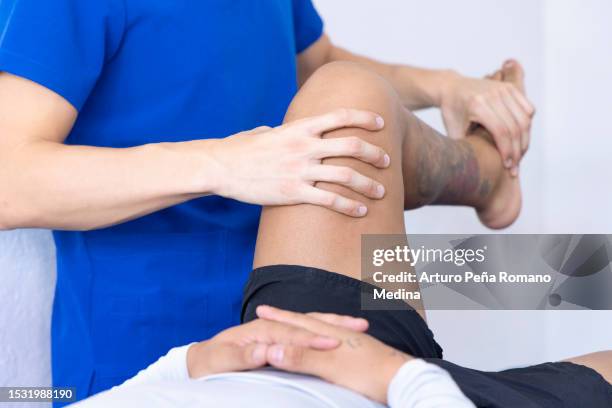 physiotherapist checking the functionality of his patient's legs. - sports physiotherapy stock pictures, royalty-free photos & images