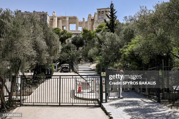 An employee closes the access gate to the Acropolis archaeological site in Athens on July 14, 2023. The ministry of culture has decided to close the...