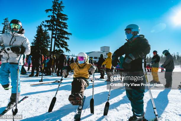 group of adaptive athletes waiting in ski lift queue - disabled extreme sports stock pictures, royalty-free photos & images