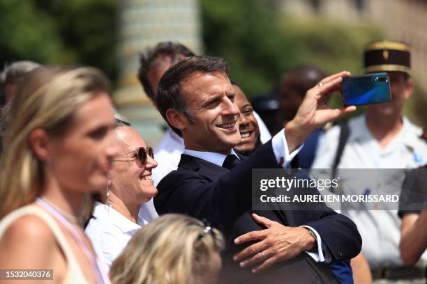 French President Emmanuel Macron takes a selfie with guests after the Bastille Day military parade on the Champs-Elysees avenue in Paris on July 14,...