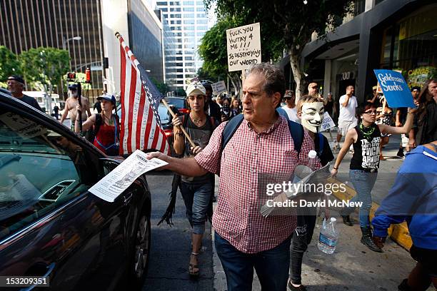 Demonstrator tries to give motorists literature as protesters march in the downtown financial district to mark the one-year anniversary of the Occupy...