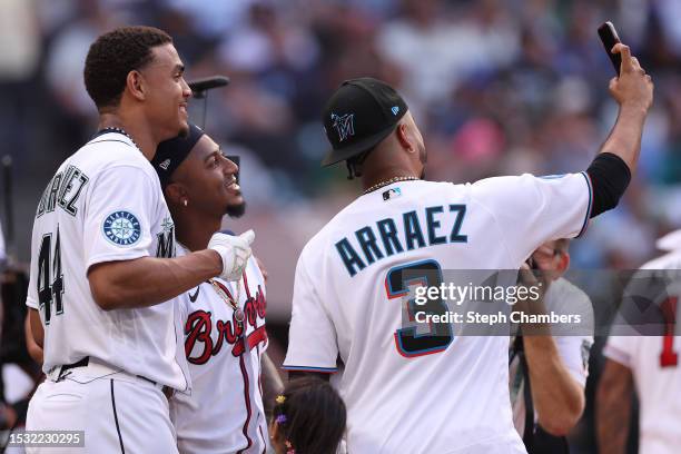 Luis Arraez of the Miami Marlins takes a selfie with Ozzie Albies of the Atlanta Braves and Julio Rodríguez of the Seattle Mariners during the...