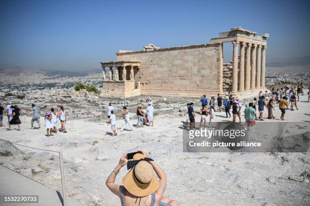 July 2023, Greece, Athen: Tourists visit the Parthenon Temple on the Acropolis Hill on this hot day. The Ministry of Culture has decided to close the...