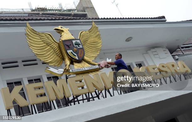 An Indonesian man cleans the country's symbol Garuda Pancasila , a mythical golden eagle with a heraldic shield on its chest, which is attached on a...