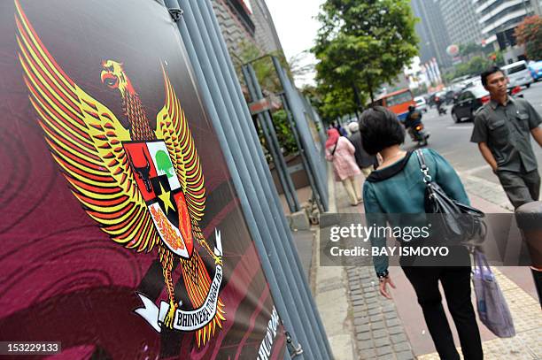 Pedestrians walk past the Indonesian symbol of Garuda Pancasila , a mythical golden eagle with a heraldic shield on its chest, which is attached on a...