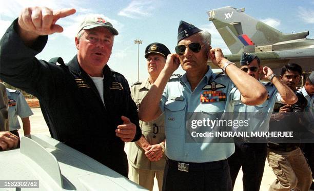 Indian Air Force Chief A.Y. Tipnis closes his ears to block the roar of a Sukhoi aircraft flying overhead as BAE Systems test pilot Gordon McClymont...