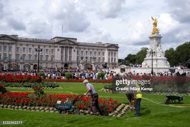 Gardeners attending to turf as tourists and domestic visitors outisde Buckingham Palace wait in huge numbers for Changing of the Guard to take place...