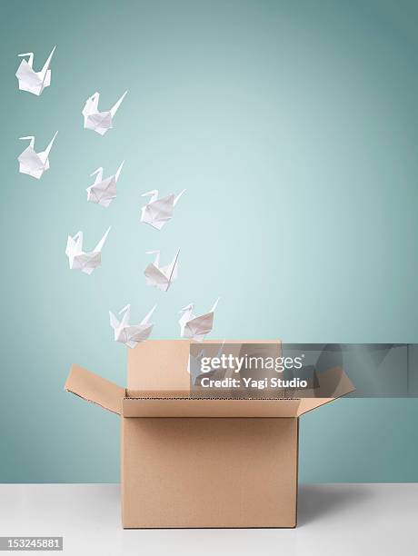 group of origami cranes flying away from cardboard - origami a forma di gru foto e immagini stock