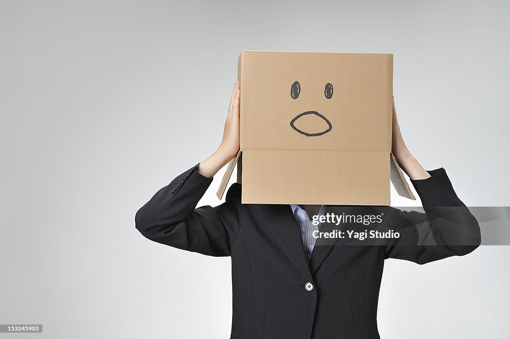 Woman poses with cardboard box over her head.