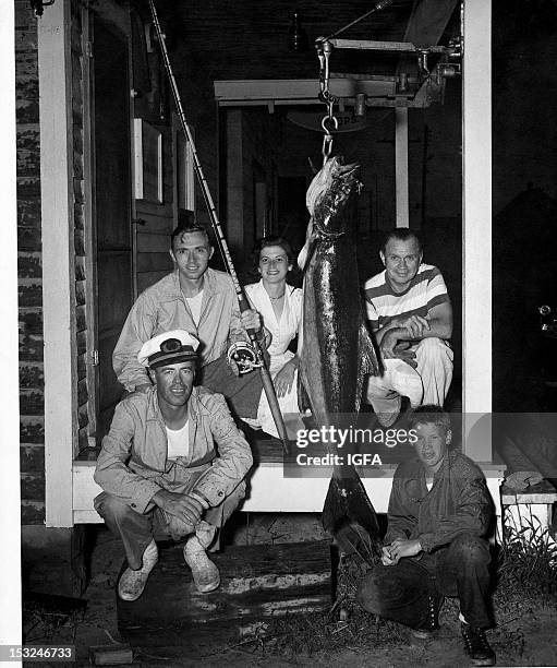 Four men and one woman kneel on a porch next to a 90 pound cobia caught near Ocean City, Maryland on August 31, 1949.