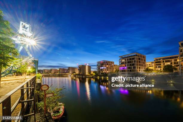 July 2023, Hesse, Offenbach: The residential quarter on the harbor island and the historic crane are located in the "blue hour". The former...