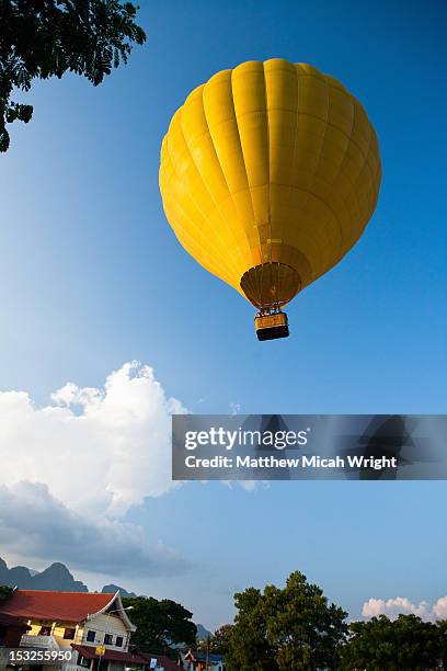a hot air balloon floats away. - vang vieng balloon stock pictures, royalty-free photos & images