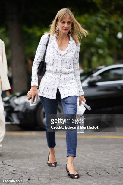 Guest wears silver and pearls pendant earrings, a white V-neck tank-top, a white with embroidered black checkered pattern tweed jacket from Chanel, a...