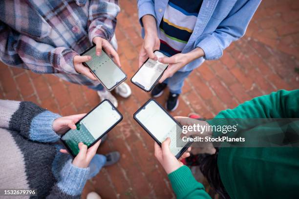 adolescenti in cerchio che tengono in mano telefoni cellulari intelligenti e scrivono un messaggio - bambini maschi foto e immagini stock