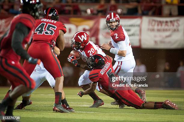 Quarterback Joel Stave of the Wisconsin Badgers hands the ball off to teammate running back James White as he's wrapped up by corner back Josh...