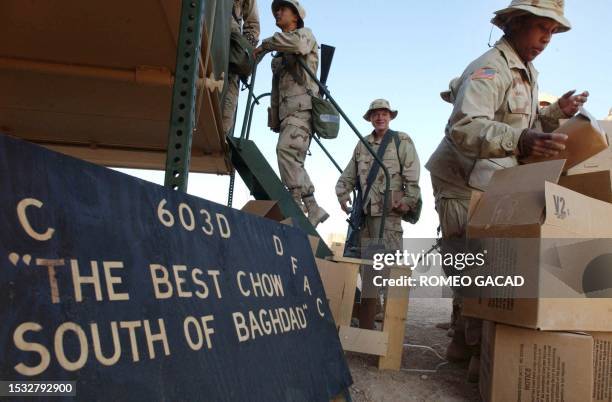 Soldiers wait in line outside the mobile dining facility of the 603rd Aviation Support Battalion 16 March 2003 advertising "The Best Chow South of...