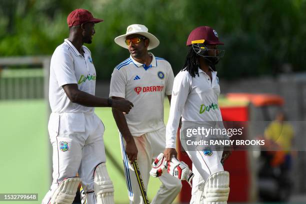 Ravichandran Ashwin of India, Jason Holder and Jomel Warrican of West Indies walks off the field at the end of day three of the First Test between...