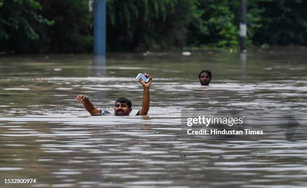 People wades through a flooded road after a rise in the water level of the river Yamuna after heavy monsoon rains, near Salimgarh Fort Ring road on...