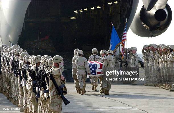 Soldiers salute during a repatriation ceremony for the remains of a helicopter crew at Bagram Air Base 25 March 2003 in Afghanistan. The crew of six...