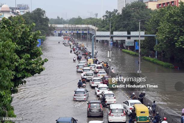 Commuters make their way through the waterlogged ITO road due to the rise in water levels of Yamuna river following heavy monsoon rains, on July 14,...
