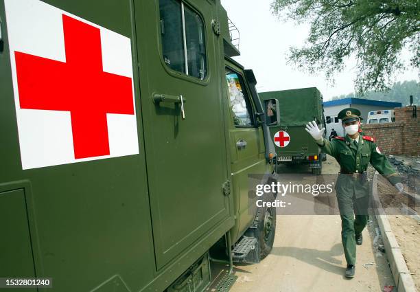 Chinese paramilitary guard shoos away photographers as a convoy of military ambulances arrive at the hospital erected in barely a week to house a...