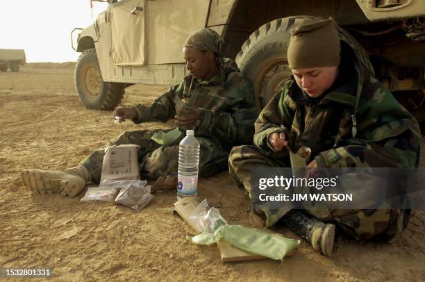Jenna Dietsch of Kalamazoo, MI, and SPC Tonya Stevenson of Orlando, FL, sort through their MREs for breakfast early 31 March 2003 at Forward Ammo and...