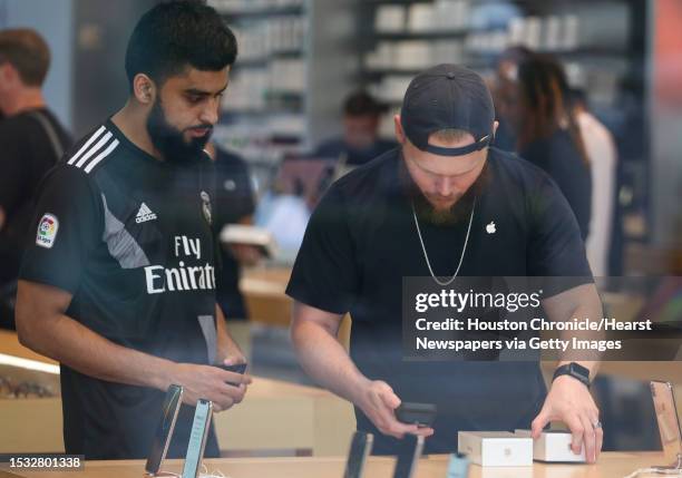 An Apple store staff helps an early customer make purchases of new products at the Highland Village Apple at 8 a.m. On Friday, Sept. 21 in Houston....