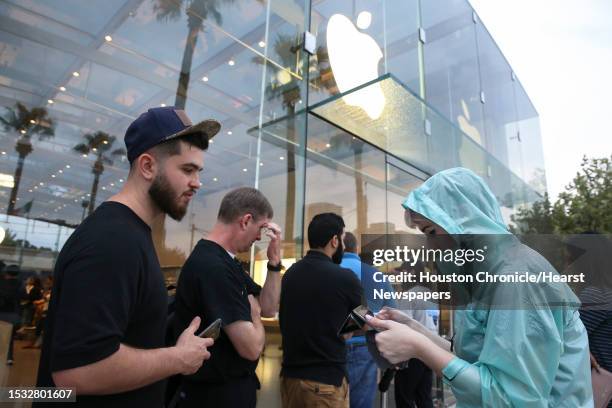 Apple store staff Kristen Hanks helps early customers to check in to purchase the new products at the Highland Village Apple store before doors open...