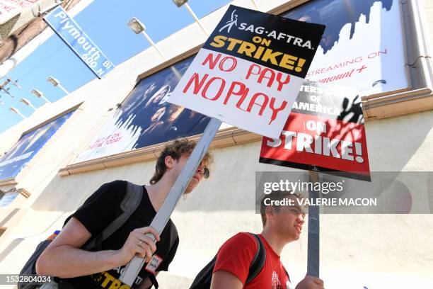 Members of the Writers Guild of America and the Screen Actors Guild walk a picket line outside Paramount Studios in Los Angeles, California, on July...