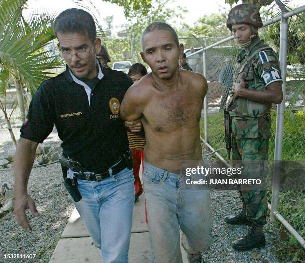 Member of the Venezuelan Intelligence and Prevention General Direction walks with an alleged Colombian paramilitary militant, in Caracas, after his...