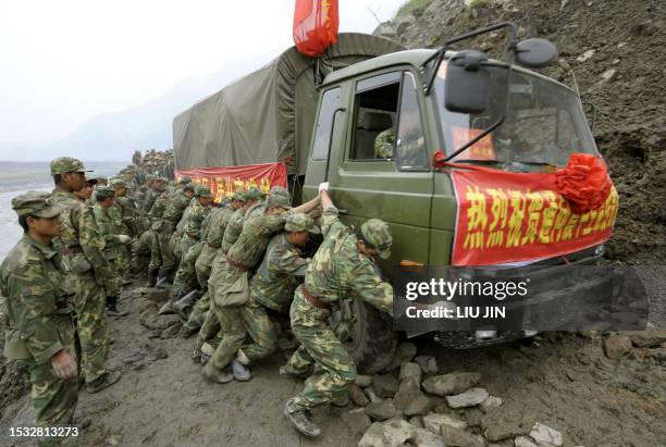 Chinese soliders push a military truck containing aid on a rough road linking the earthquake-hit Yingxiu town in Wenchuan county, after a quake with...