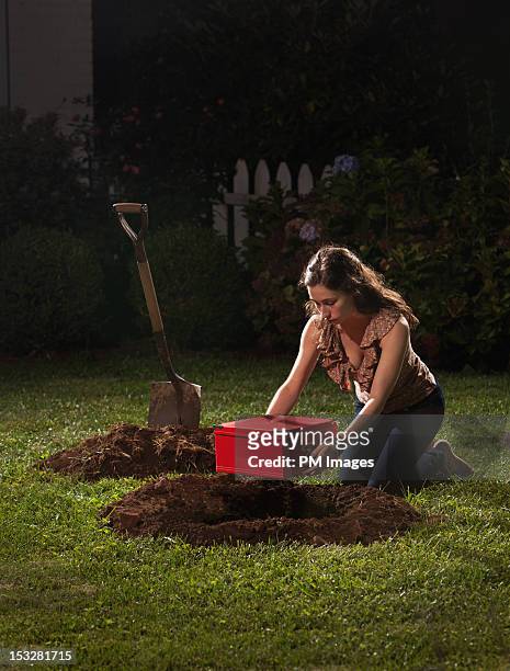 young woman burying red box - burying stockfoto's en -beelden