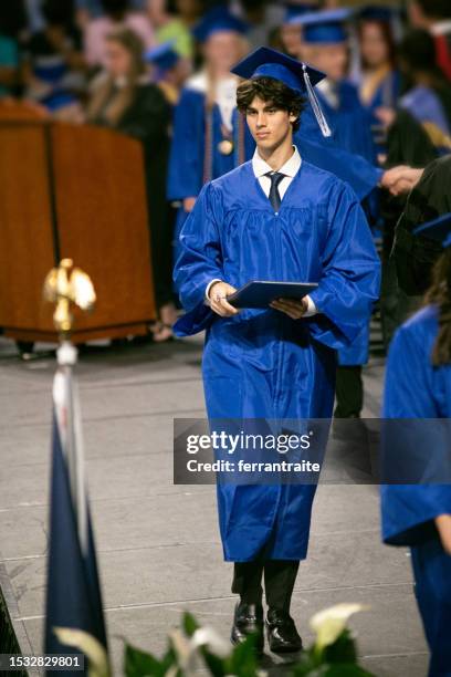 high school students pick up diplomas during the graduation ceremony - laatstejaars high school stockfoto's en -beelden